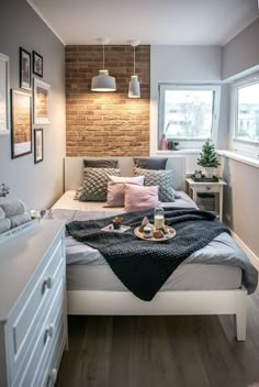 a bedroom with brick wall and white bedding in the corner, along with two windows