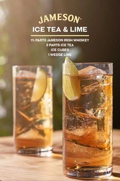 two glasses filled with ice tea and lime on top of a wooden table next to each other