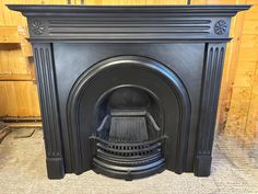 a black fireplace with a wooden wall behind it