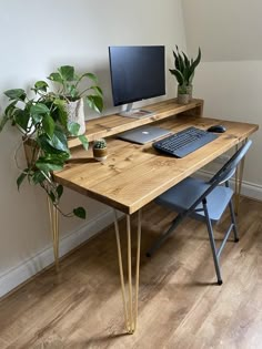 a wooden desk with a computer on top of it next to a potted plant