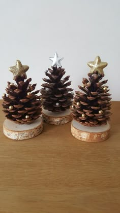 three small pine cones with gold decorations on them sitting on top of a wooden table