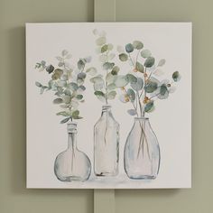 three glass vases with flowers in them on a wall