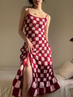 a woman in a red and white crocheted dress is standing on a bed