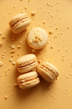 three macaroons sitting on top of a yellow surface covered in tiny white flecks