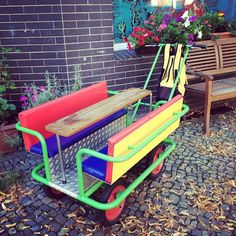 a colorful cart sitting in front of a brick building next to a bench and table