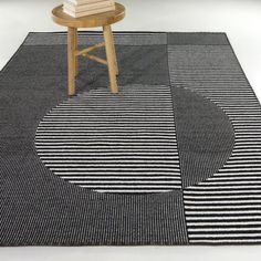 a black and white striped rug with a wooden chair in the middle on top of it