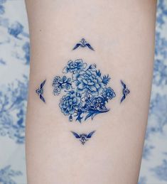 a blue and white flower tattoo on the right side of the leg, with birds flying around it