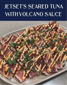 a platter filled with sliced tuna covered in sauce