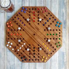 a wooden board game set with dices and numbers on it next to a glass of beer