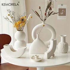 three white vases sitting on top of a table next to each other with flowers in them