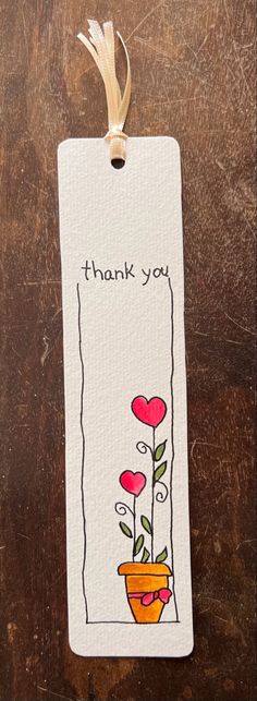 a thank card with flowers in a pot on top of a wooden table next to a ribbon