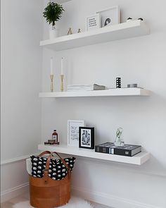 a white shelf with some books and a bag on it