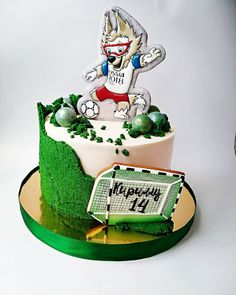 a birthday cake decorated with an image of a cartoon character on top of grass and soccer balls