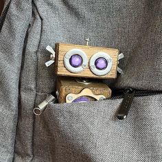 a small wooden toy with two eyes sticking out of it's pocket