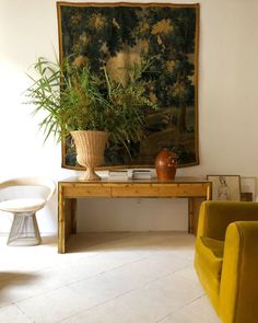 a living room with two yellow chairs and a painting on the wall above it's coffee table