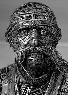 a sculpture of a man with metal wire on his face and beard, in black and white