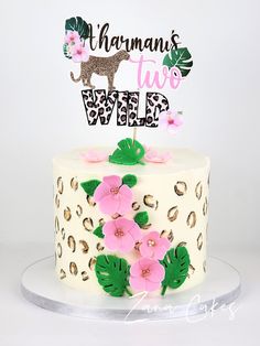 a white cake with pink flowers and a leopard print on the top that says,'ahanan's two wild '