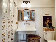 a white sink sitting under a mirror next to a toilet in a room with lots of drawers