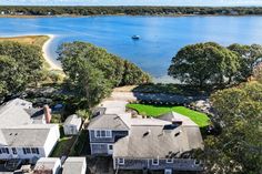 this is an aerial view of the house and its surrounding land, with water in the background