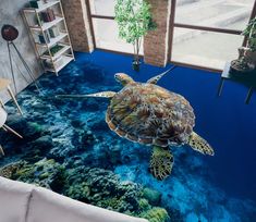 a sea turtle swimming in the ocean on a blue floor with corals and plants