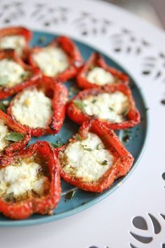 small stuffed peppers on a blue plate with cheese and herbs in the middle, ready to be eaten