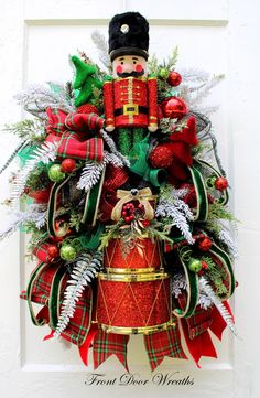 a christmas wreath with a nutcracker in the middle and evergreens on top