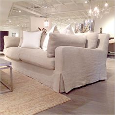 a living room filled with lots of white furniture and pillows on top of a rug