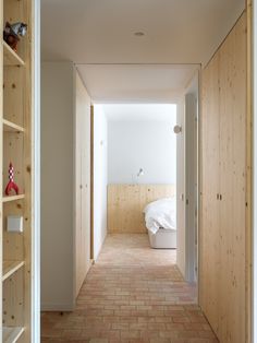 an empty hallway leading to a bedroom with a bed in the corner and shelves on either side