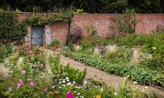 an old brick building surrounded by flowers and greenery