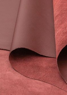 two brown leather sheets laying on top of each other, with one rolled up in the middle