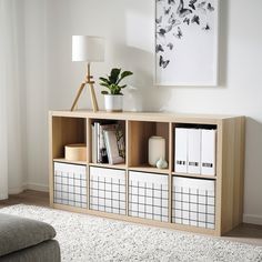 a living room with a book shelf, lamp and pictures on the wall above it