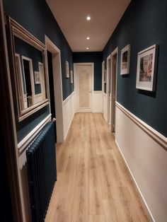 an empty hallway with blue walls and white trim on the wall, wood flooring and radiator