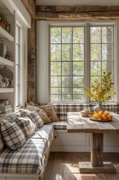 a window seat in the corner of a room next to a table with oranges on it