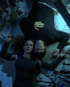 two people laying on the ground surrounded by papers