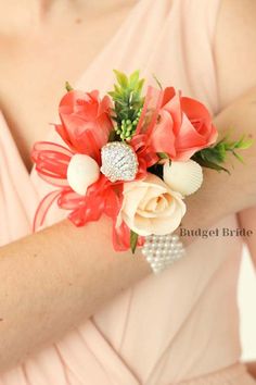 a bridesmaid's wrist corsage is adorned with coral and white flowers