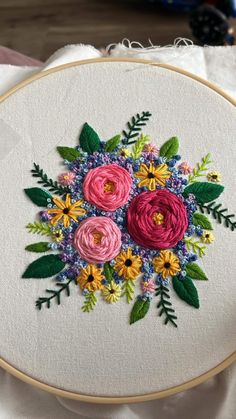 a close up of a embroidery on a piece of cloth with flowers in the center