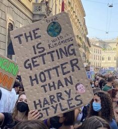 a group of people holding signs and wearing face masks in the middle of a street