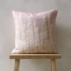 a pink and white pillow sitting on top of a wooden stool