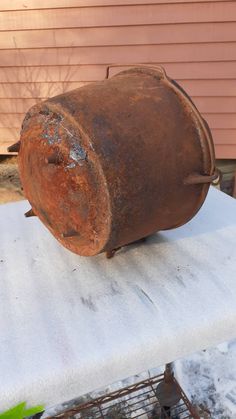 an old rusted metal pot sitting on top of a white bench outside in the snow