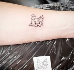 a small tattoo on the arm of a woman with a fox and dog head drawn on it