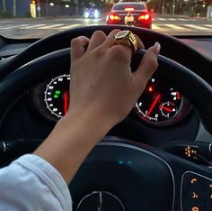 a person driving a car with their hand on the steering wheel and dashboard lights in the background