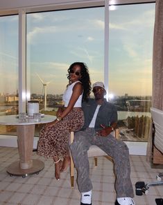 a man and woman sitting on a chair in front of a window with windmills