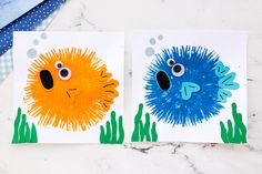 two handprinted cards with blue and orange puffer fish on them, one is yellow and the other is red