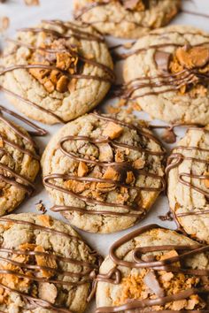 cookies with chocolate drizzled on top and peanut butter in the middle, sitting on a baking sheet