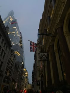 the british flag is flying high in the sky above some buildings and people walking down the street