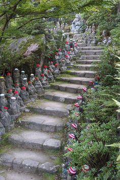 many statues are lined up on the stone steps in front of some trees and bushes