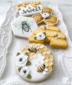 decorated cookies on a white plate with flowers and honeycombs in the shape of bees