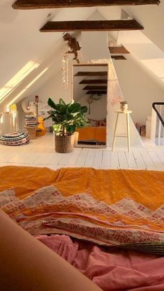 a bedroom with an orange bed spread on the floor next to a plant in a pot