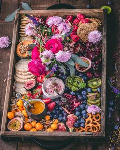 a wooden box filled with lots of different types of food and flowers on top of it