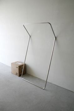 a white wall with a metal frame and a cardboard box on the floor next to it